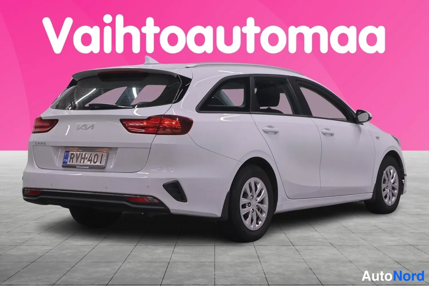 Takaviisto: Auton takaosa kolmesta neljänneksestä vasemmalta: valkoinen farmariauto, takavalot ja farmarin takaluukki näkyvät, rekisteritunnus.