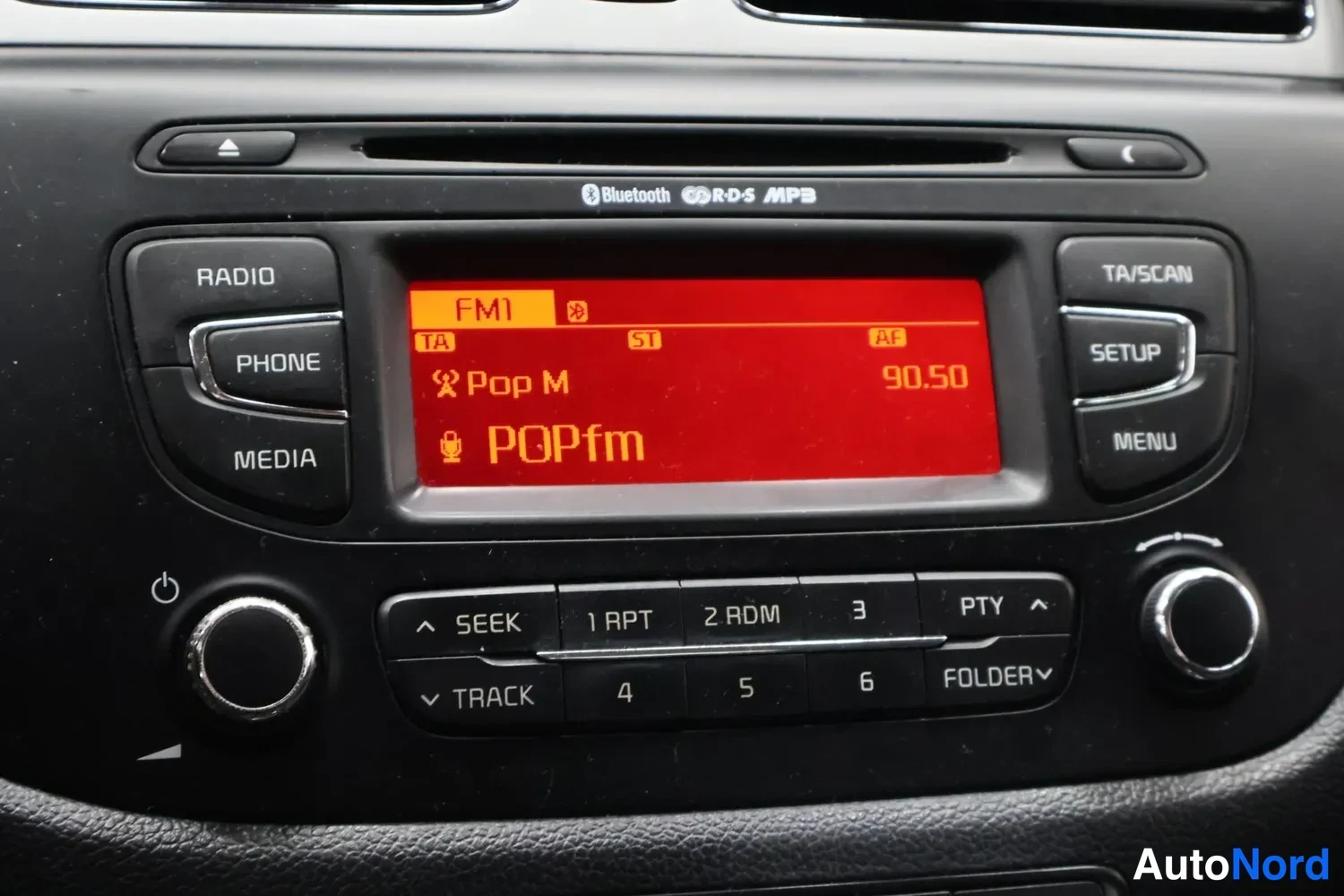 Yksityiskohta: Auton radionäyttö päässä FM1-kanavalla 90.50 MHz, äänitehtävä Pop M ja POPfm tekstinä, radiopaneelin yhteydessä RADIO-, PHONE-, MEDIA-, TA/SCAN-, SETUP- ja MENU