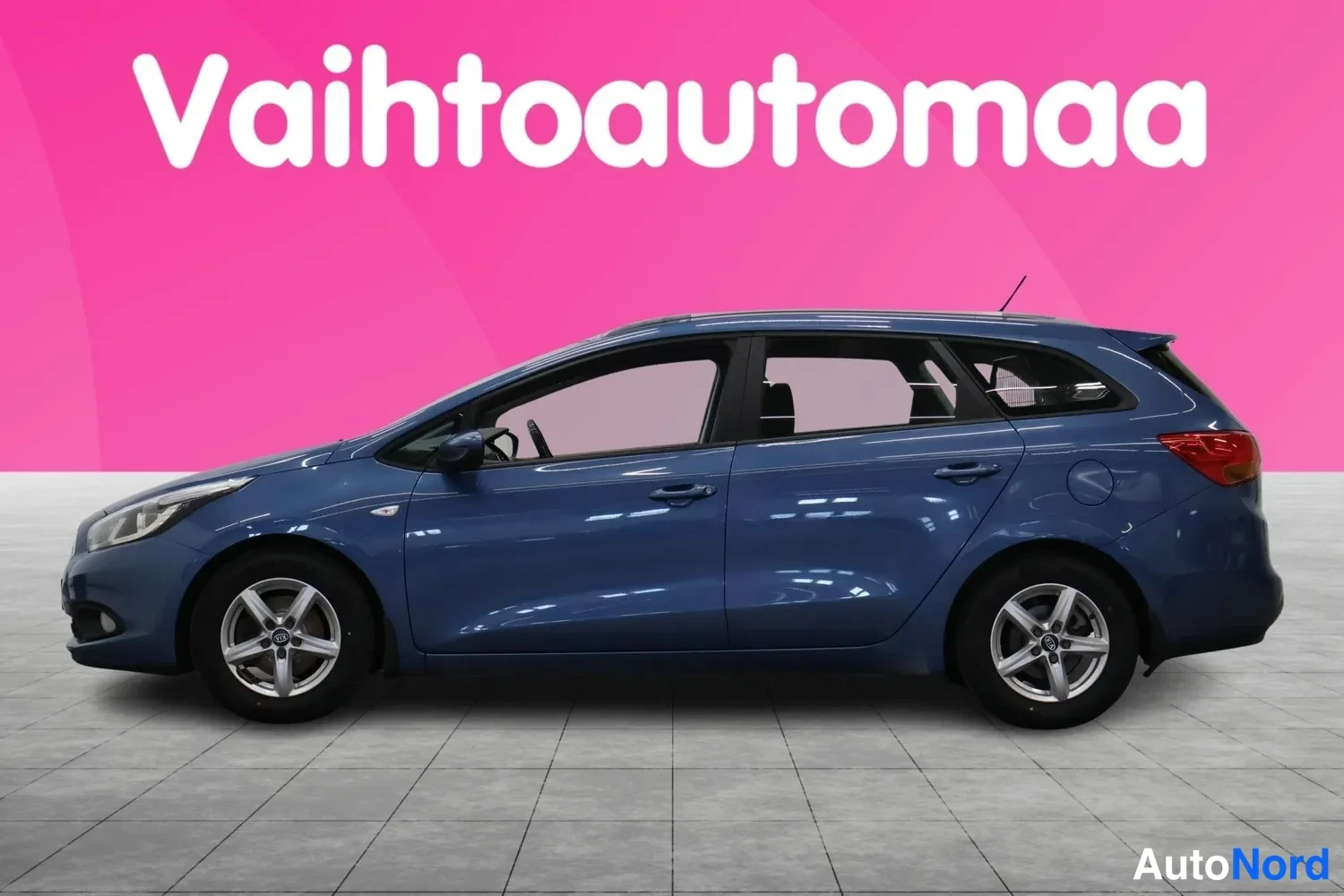 Etuviisto, nokka vasemmalle: Sininen Kia Ceed -farmariauto sivusta etuviistöstä kuvattuna vaaleassa studiossa.