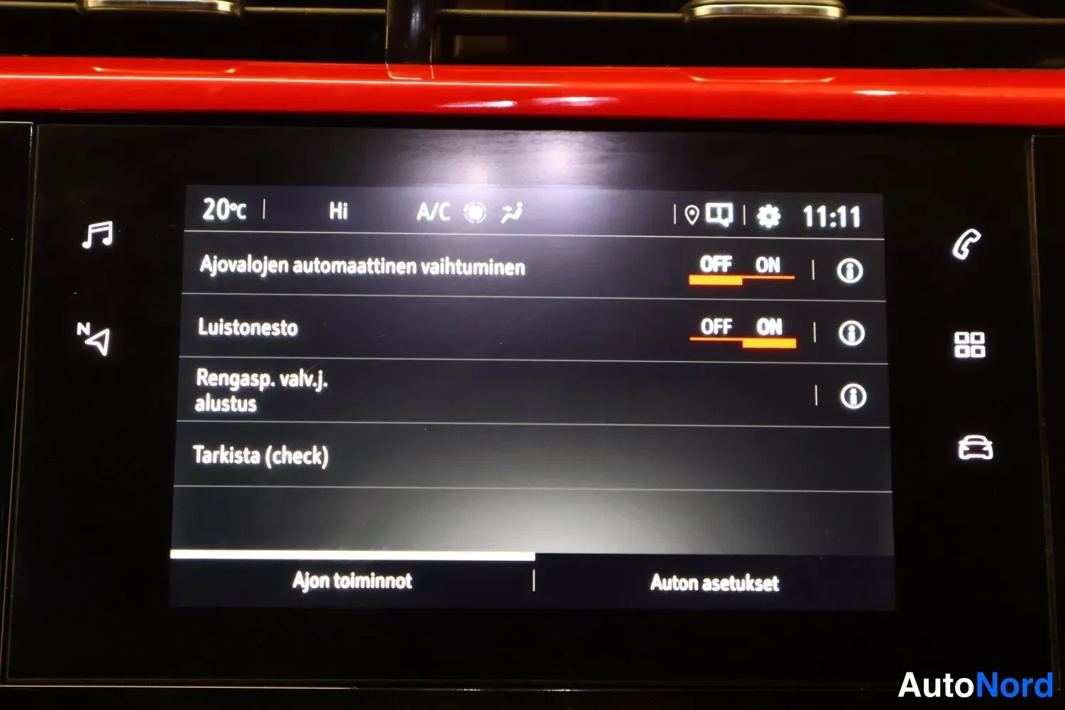 Yksityiskohta: Kojelaudan näyttö, jossa on auki Ajon toiminnot -valikko kohdilla Ajovalojen automaattinen vaihtuminen, Luistonesto, Rengasp. valv.j. alustus ja Tarkista (check