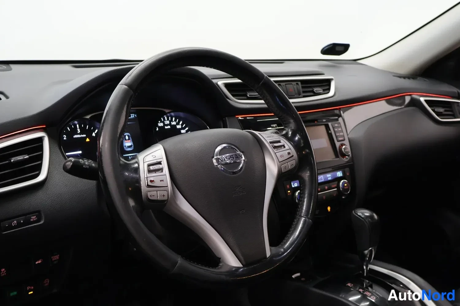 Edestä: Sisätilakuva auton etupenkiltä: Nissan-ohjauspyörä, mittaristo ja kojetaulu näkyvät.