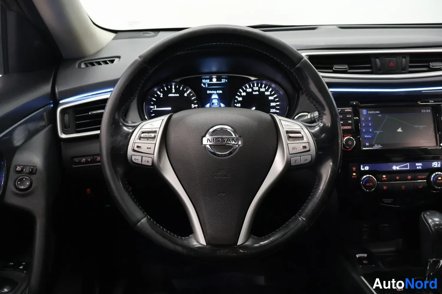 Edestä: Ohjauspyörä ja mittaristo suoraan edestä kuvattuna, Nissan-merkki ohjauspyörässä.