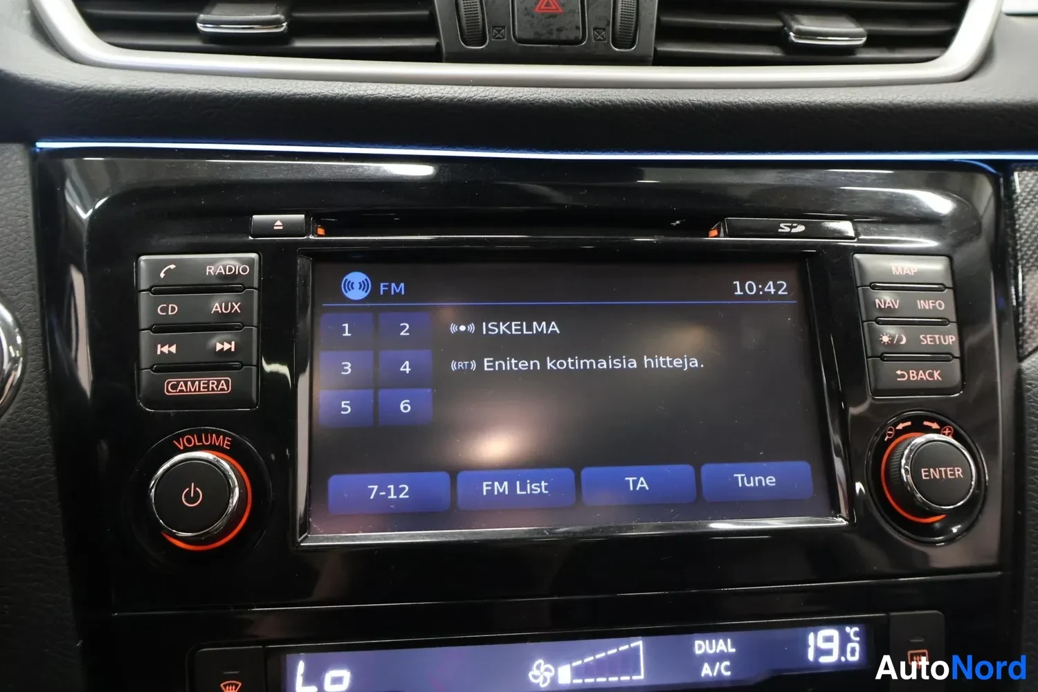 Muu: Kosketusnäyttö näyttää FM-radiolistan asemalla ISKELMA, teksti 'Eniten kotimaisia hitteja', kello 10:42.
