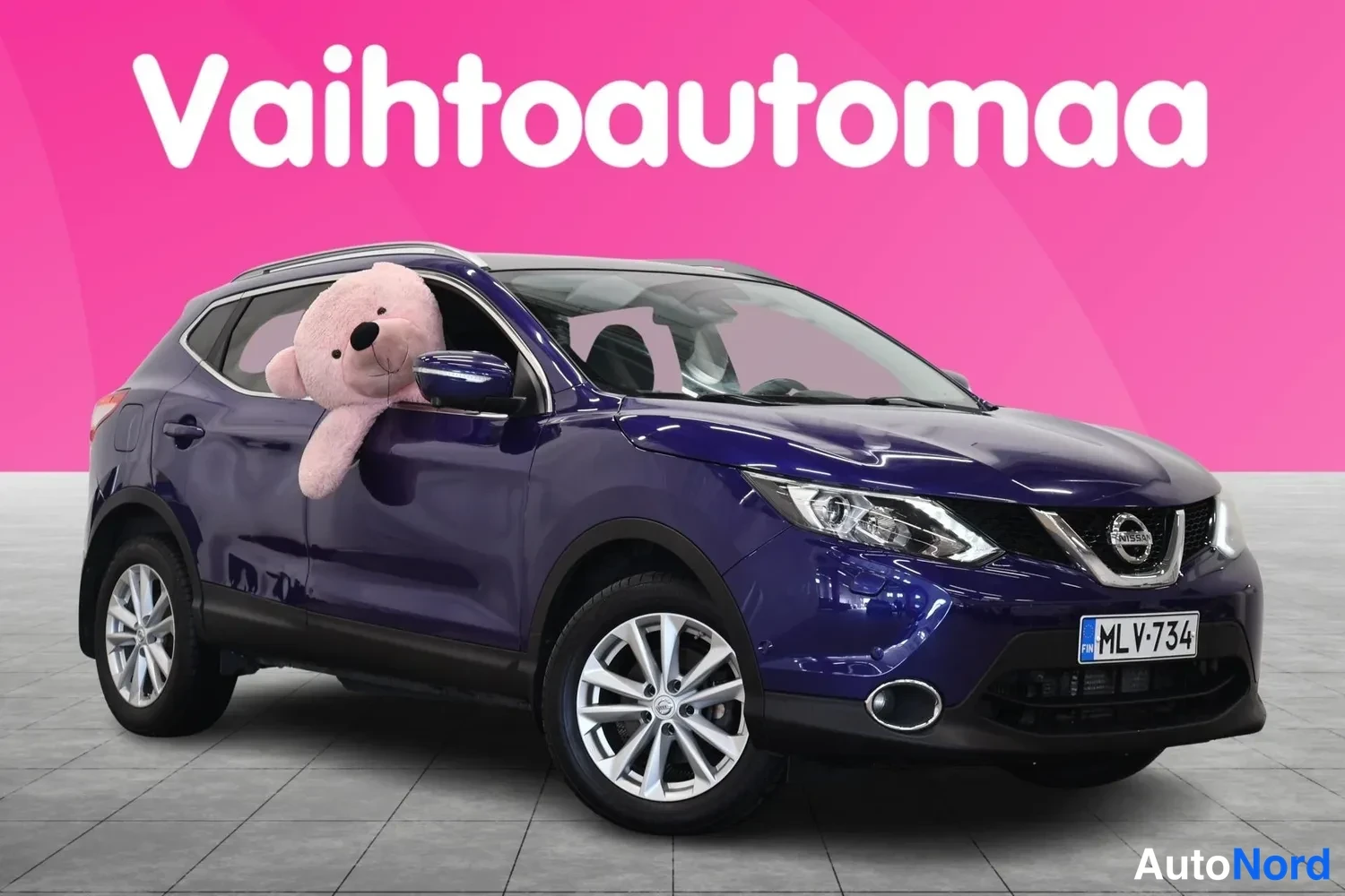 Etuviisto, nokka oikealle: Sininen Nissan Qashqai kolmanneltasektoralta edestä, keulanosa ja vasen sivu näkyvissä, pehmoauto autossa ikkunasta kurkkimassa.