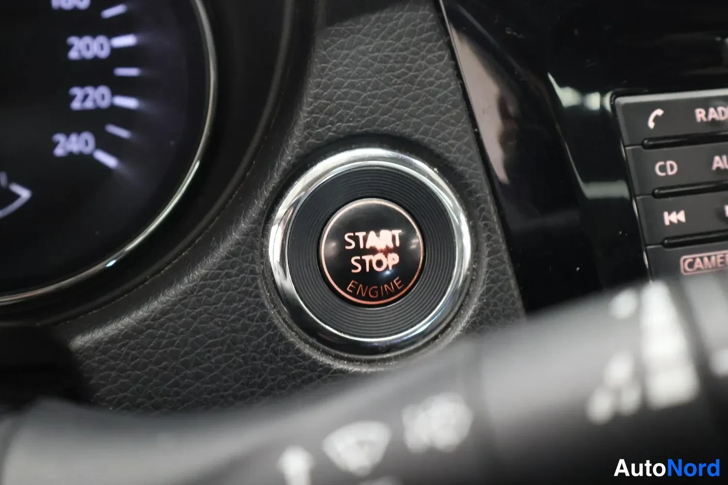 Muu: Kojelaudan käynnistyspainike, jossa tekstit START STOP ENGINE, raton taustalla nähden.