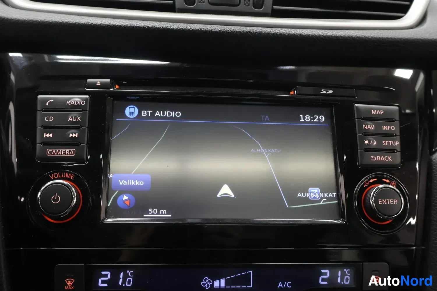 Yksityiskohta: Ristikon kojelaudan keskikonsolin näyttö näyttää BT Audio -navigaatiota, ympärillä RADIO-, CD-, AUX- ja CAMERA-napit sekä MAP-, NAV-, INFO-, SETUP- ja BACK-napi