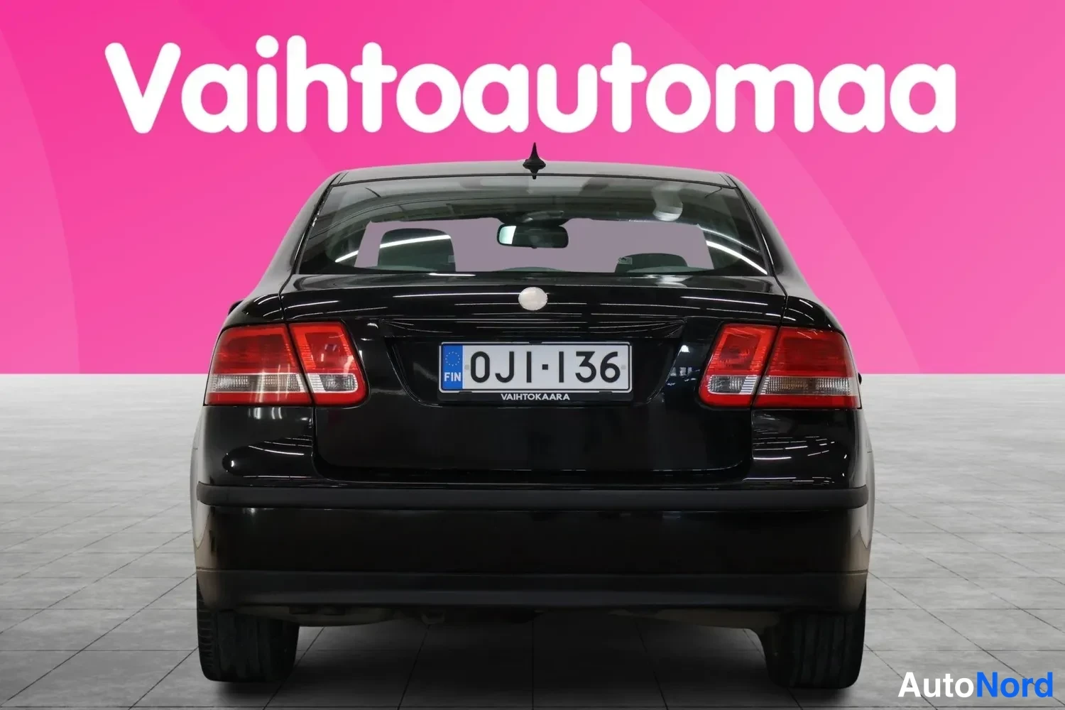 Takaa: Mustan henkilöauton takaosa suoraan takaa, punaiset takavalot ja rekisterikilpi.