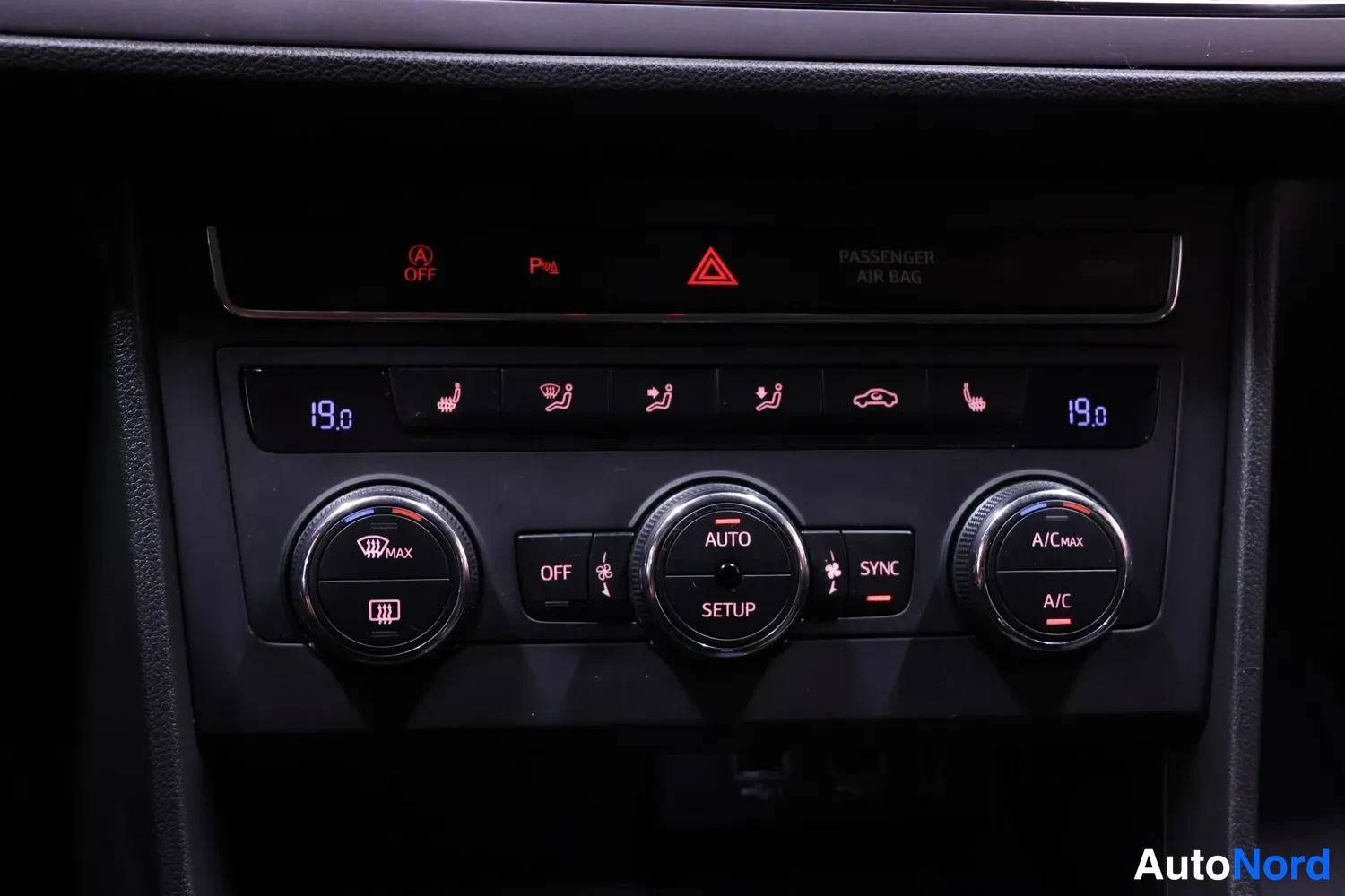 Muu: Ilmastointipaneelin lähikuva: lämpötilat 19,0 molemmin puolin ja merkit MAX, AUTO, SYNC sekä A/C ja A/C MAX.
