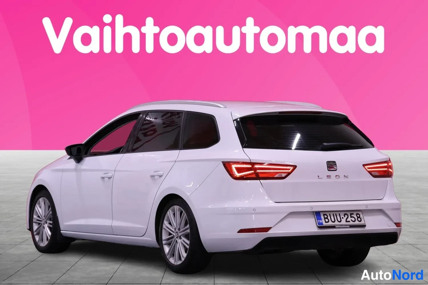 Takaviisto: Valkoinen Seat Leon ST -farmari takaa kolmannelta kulmalta, takaosan ja kyljen näkyvissä punaiset takavalot ja rekisteri.