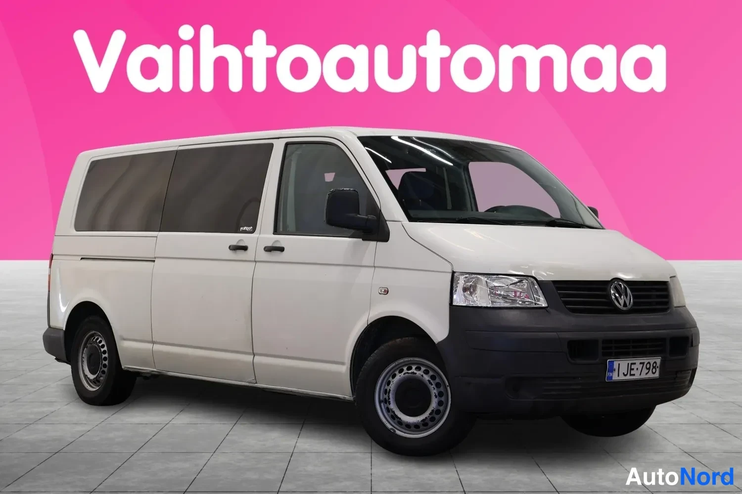 Etuviisto, nokka oikealle: Valkoinen pakettiauto kolmivartalokuva edestä oikealta, rekisterikilpi JE-798.