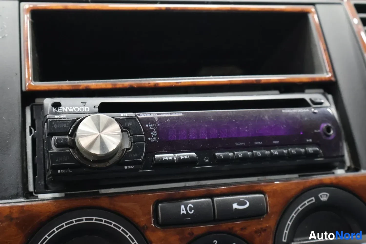 Muu: Kojeiston Kenwood-KDCLW304-CD-radion(?) kiinnitys; keskikonsoli: 'AC'-painike ja ilmastointipainike, puunrunkoinen paneeli.