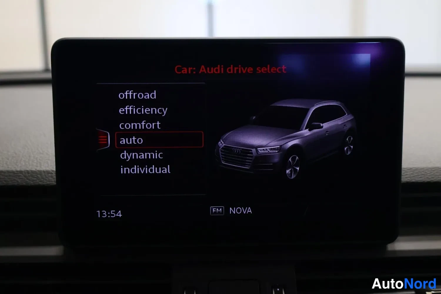 Yksityiskohta: Auton keskusnäyttö valikossa Car: Audi drive select, vaihtoehdot offroad, efficiency, comfort, auto, dynamic ja individual, auto korostettuna; näytöllä kello 13
