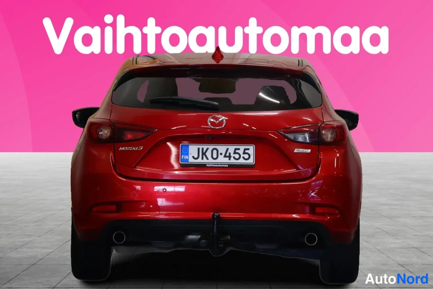Takaa: Punaisen Mazda3-hatchbackin suora takaosakuva, rekisterikilpi JK0-455, perävaunukytkin näkyvissä.