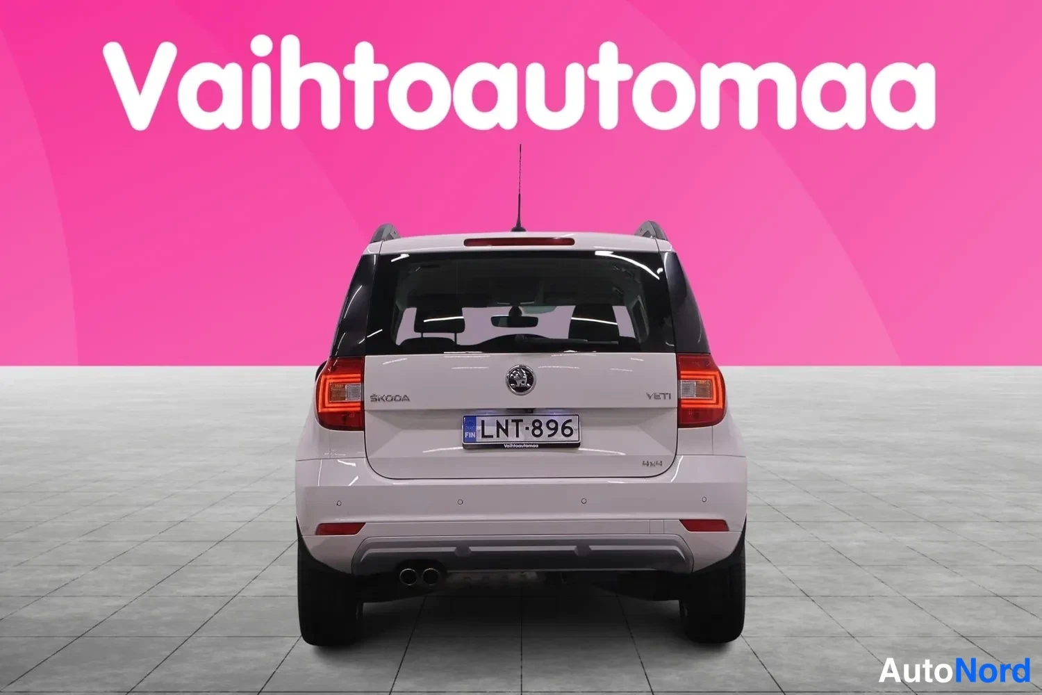Takaa: Valkoinen auto suoraan takaa, ŠKODA-merkintä ja rekisterikilpi, kaksi pakoputken päästä näkyvät takapuskurin alla.