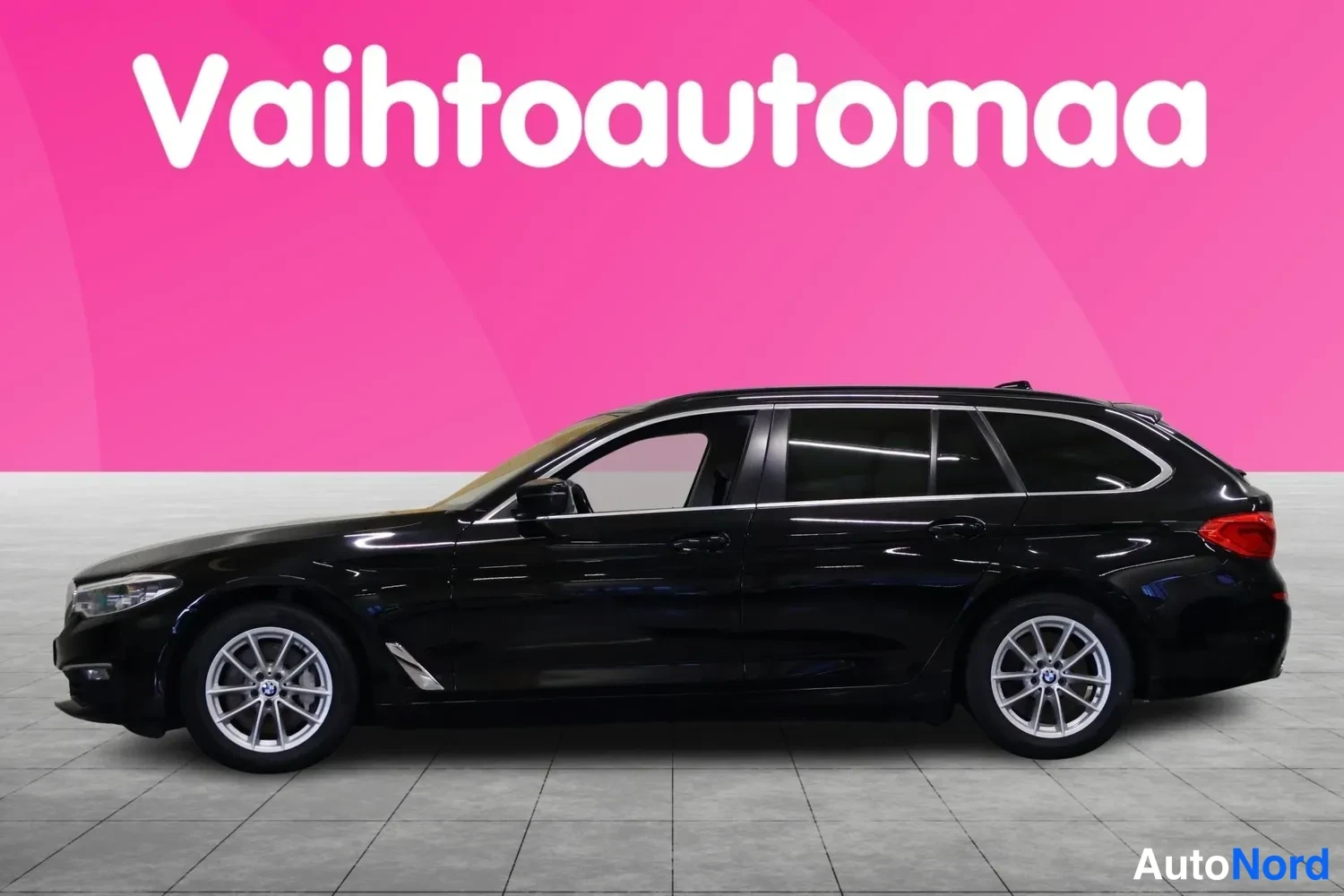Etuviisto, nokka vasemmalle: Musta farmarikori BMW sivusta etu kolmasosa, keula kuvan vasemmassa reunassa.