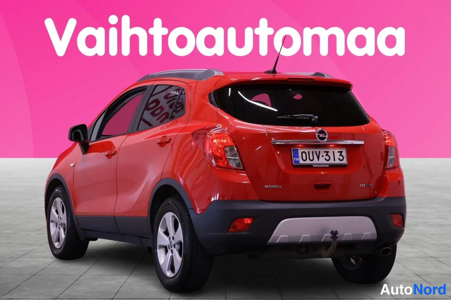Takaviisto: Opel Mokka takaa oikealta vasemmalle kuvattuna, punainen korirakenne ja takapuskurin vetokoukku näkyvät.