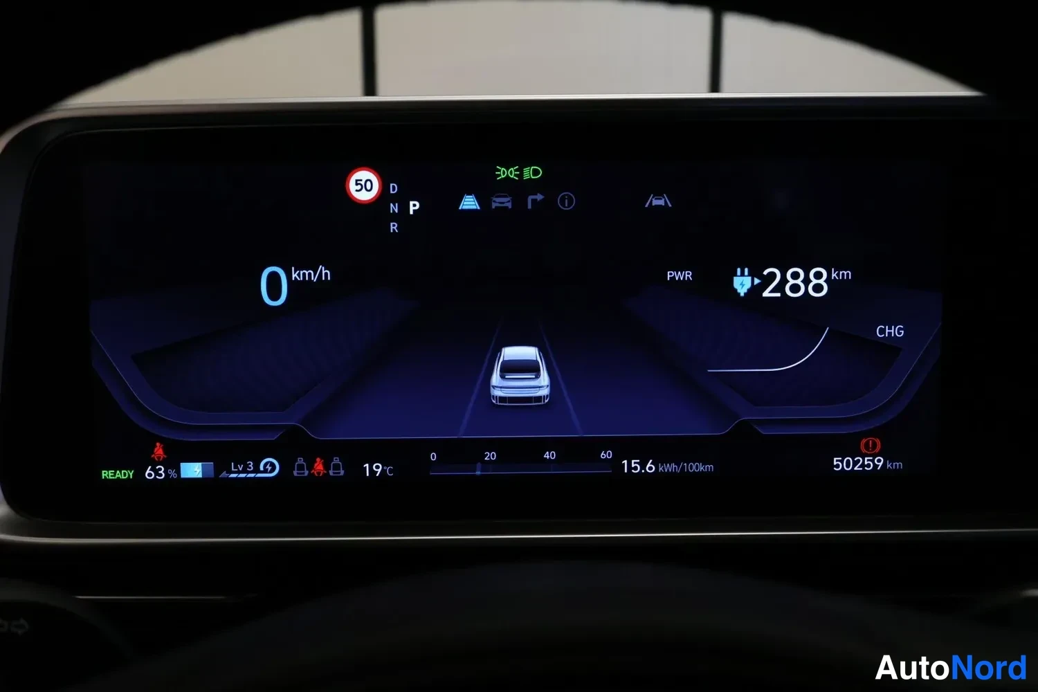 Muu: Kojetaulun digitaalinäyttö: vaihde P, nopeus 0 km/h, akun varaus 63 %, toimintasäde 288 km, kokonaislukema 50259 km ja kulutus 15,6 kWh/100 km.