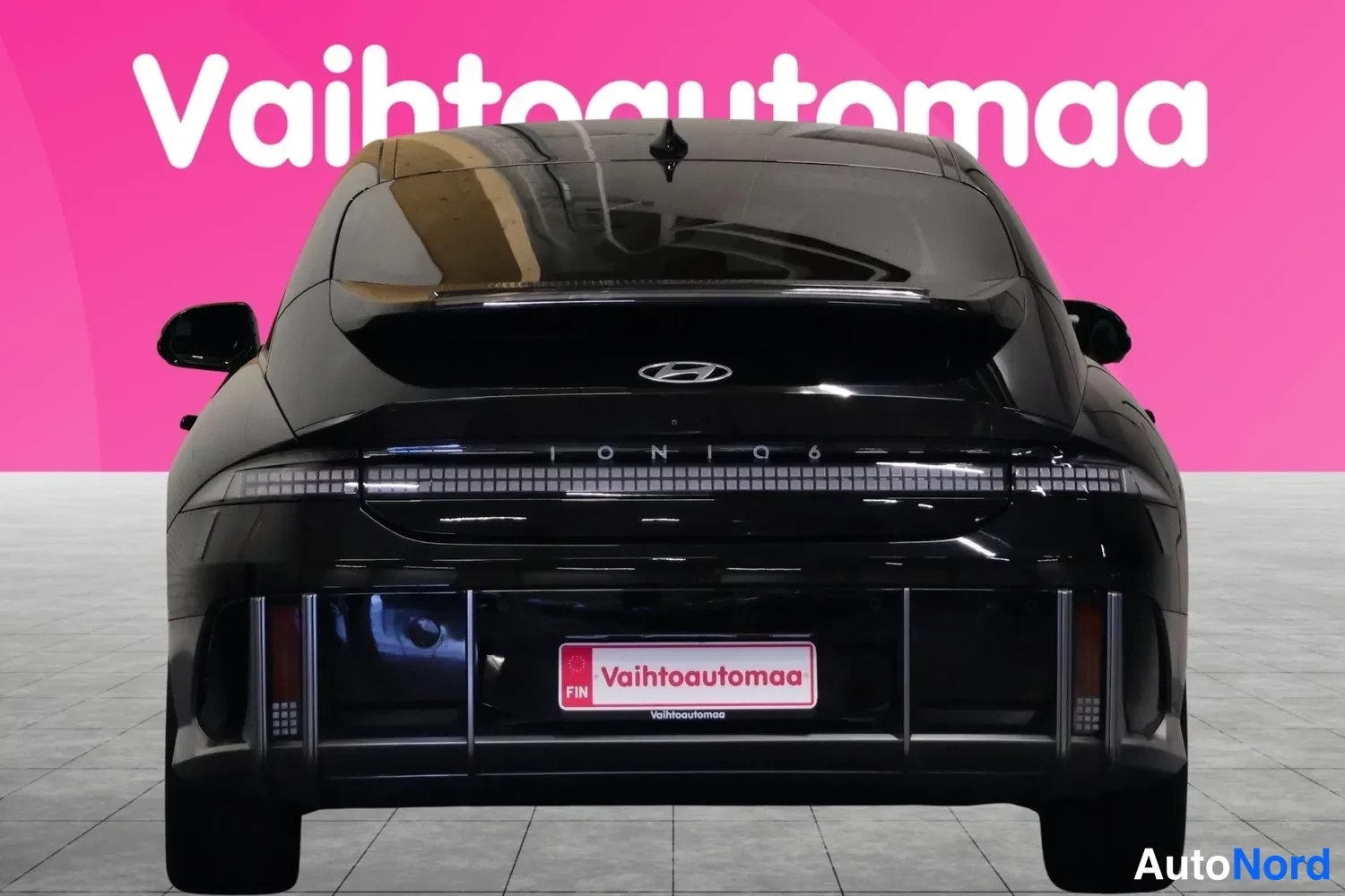 Takaa: Mustan Hyundai Ioniq 6:n suora takakuva, Hyundai-merkki ja IONIQ 6 -teksti takaluukussa, Vahtoautomaa-kyltti rekisterin paikalla.