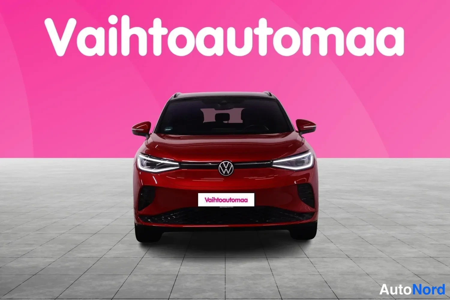 Edestä: Punaisen Volkswagenin suora edustanäkymä ilmoituksen taustagrafiikassa.