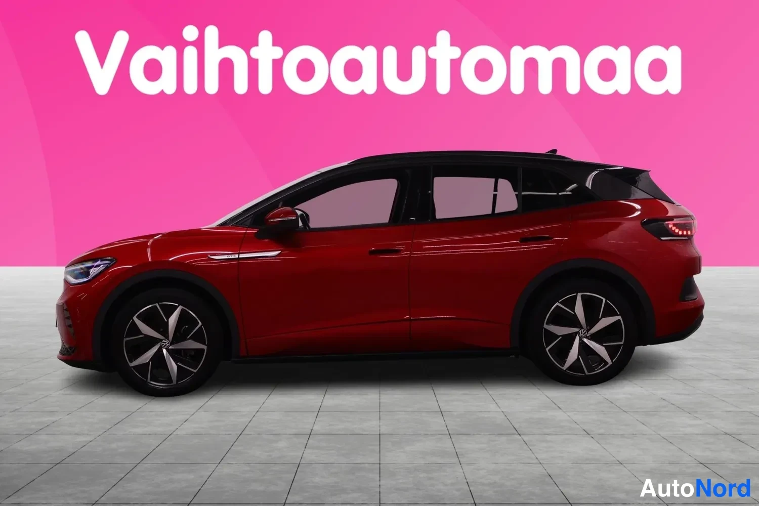 Sivulta: Punainen Volkswagen sivusta, tumma lasikatto ja kahden värikkäät vanteet, Vahtoautomaa-tunnuksella