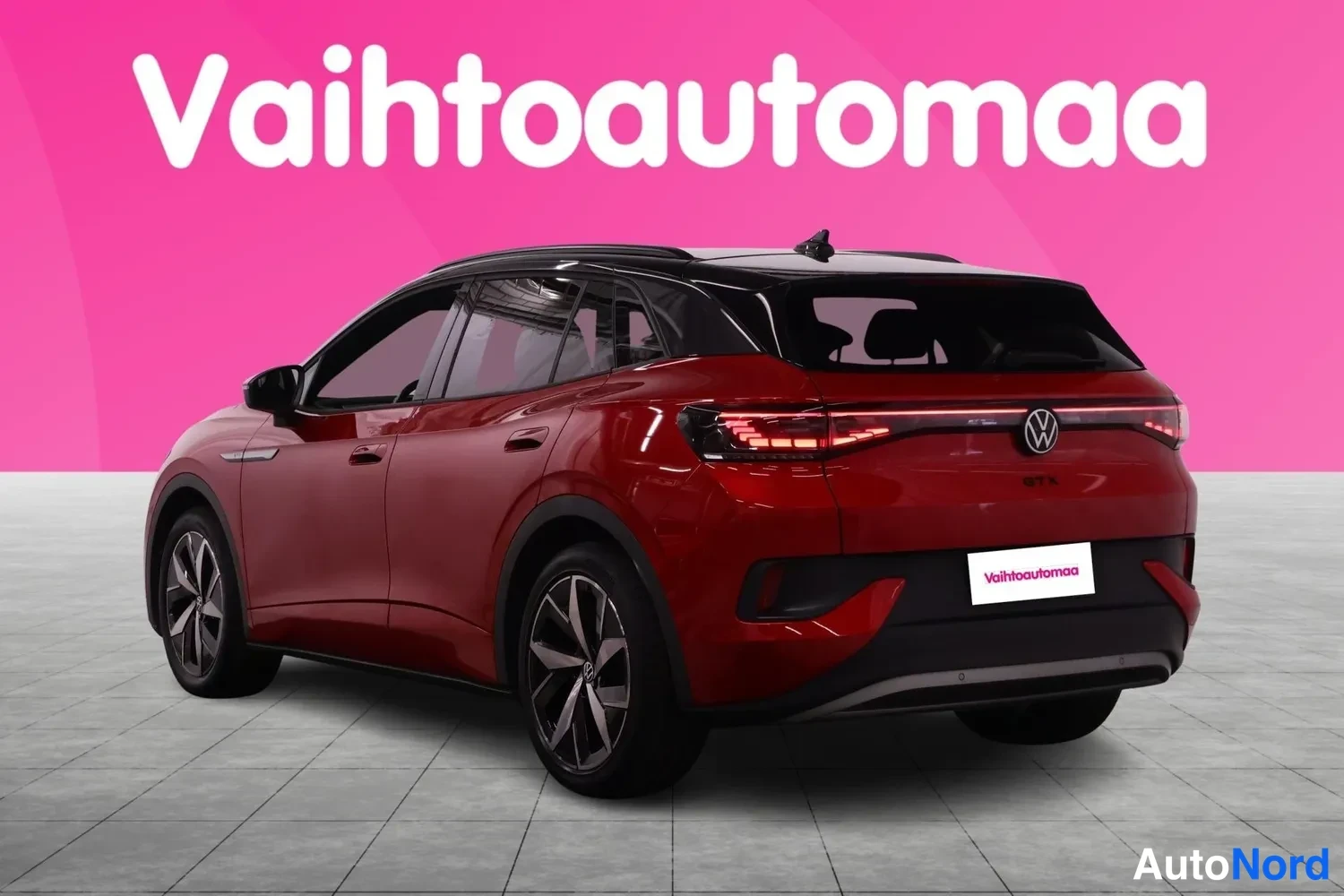 Takaviisto: Punainen Volkswagen takakulmanäkymää, tumma lasikatto ja Vahtoautomaa-tunnuksella