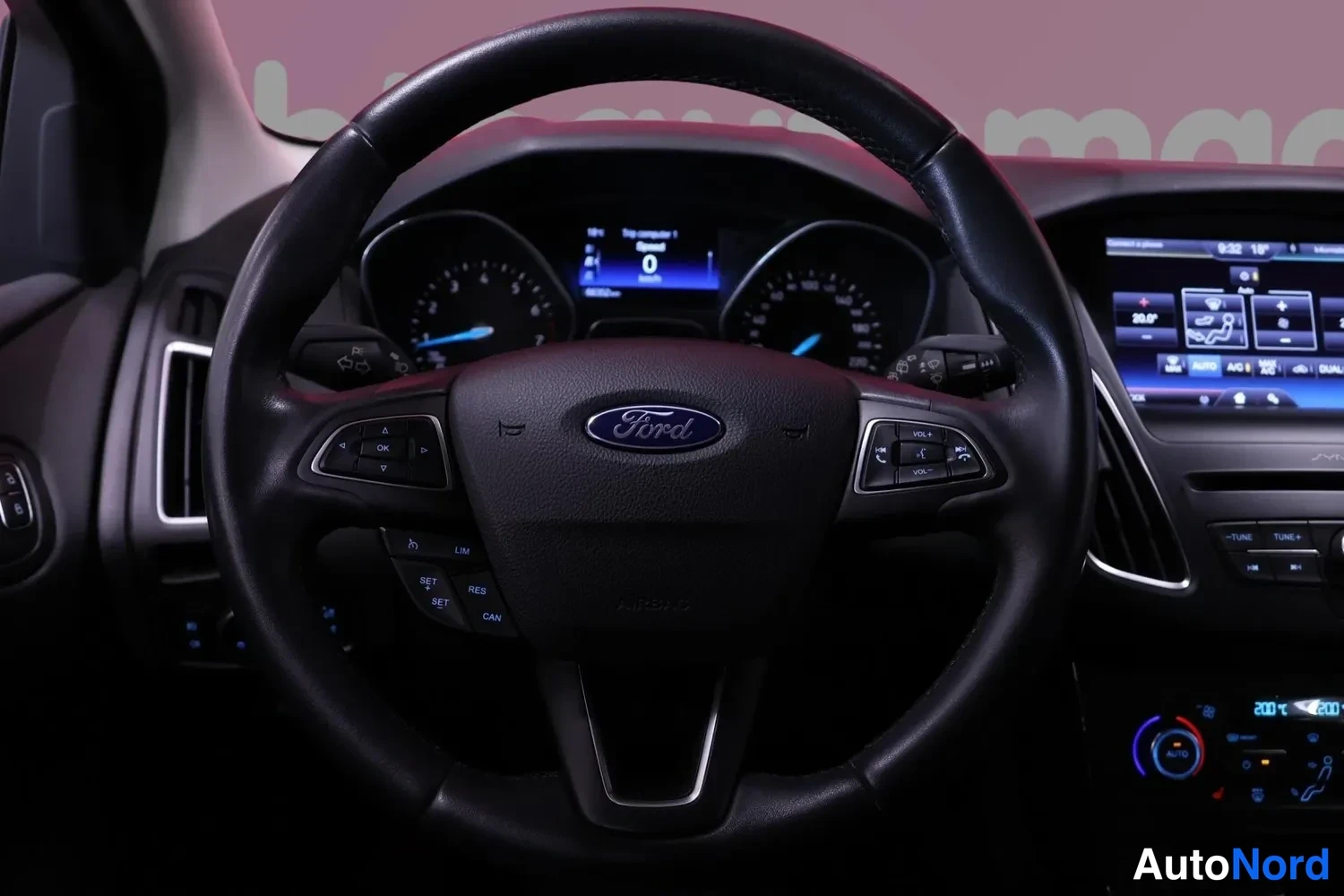 Muu: Ford-ohjauspyörä lähikuvassa, mittaristo ja infotainment-näyttö taustalla