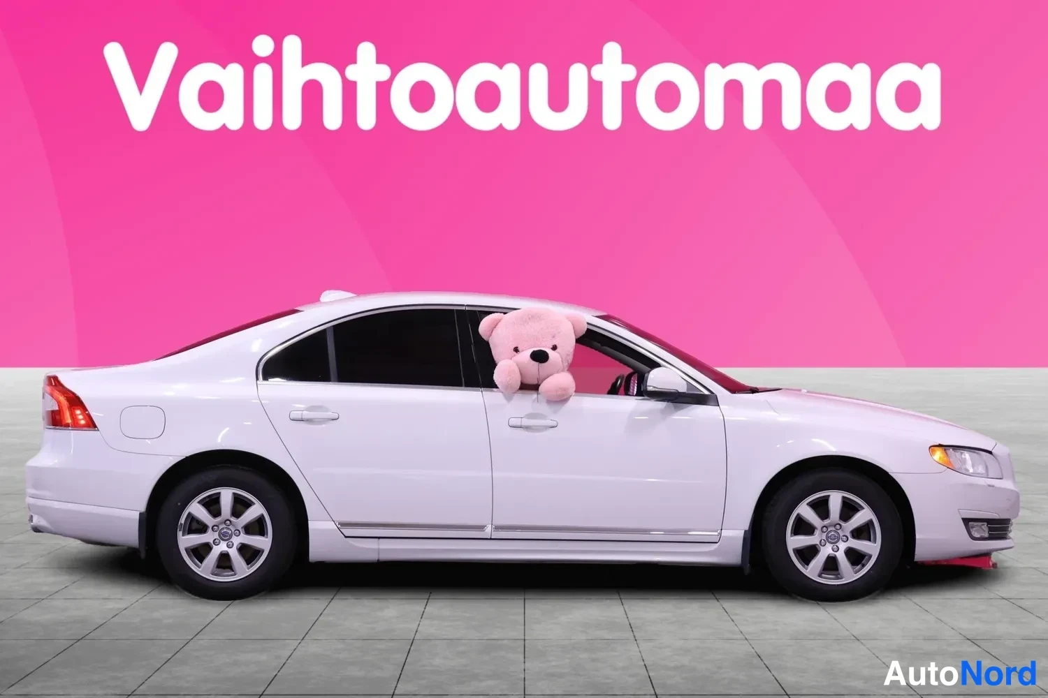 Sivulta: Valkoisen Volvo S80 -sedan vasen sivu kuvattuna sivulta, aukossa näkyy pehmolelu.