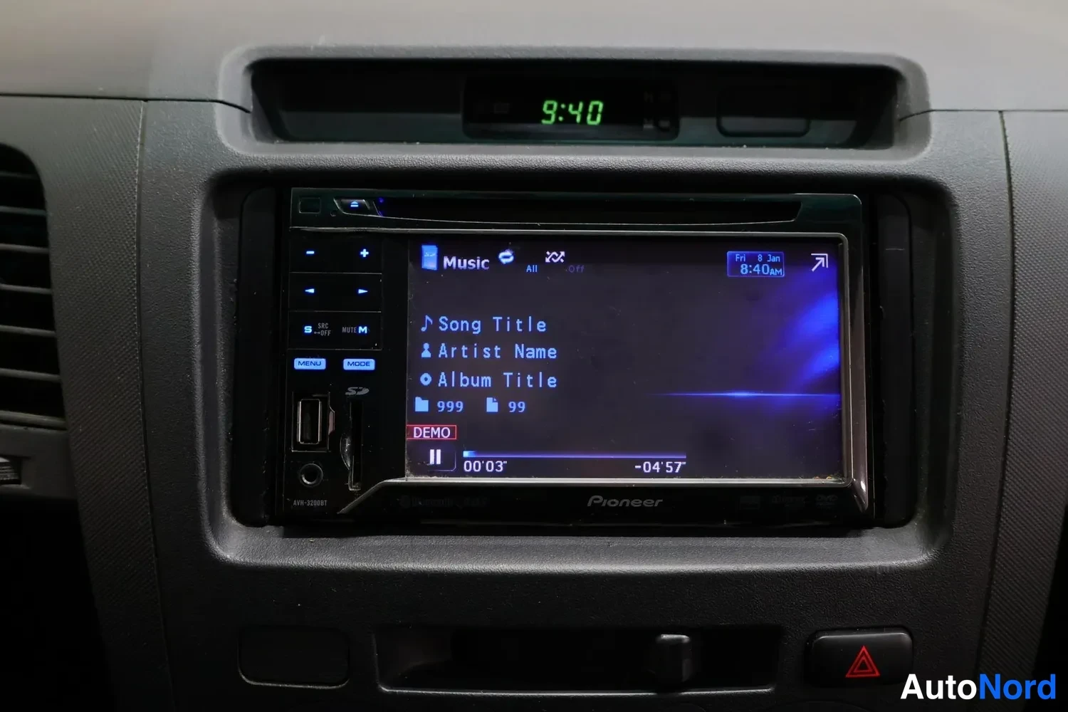 Yksityiskohta: Kojelaudan konsolissa Pioneer AVH-X280BT -radiosetti, jonka näytöllä on musiikkivalikko, kellonaika 9:40 näkyy yläpuolella.
