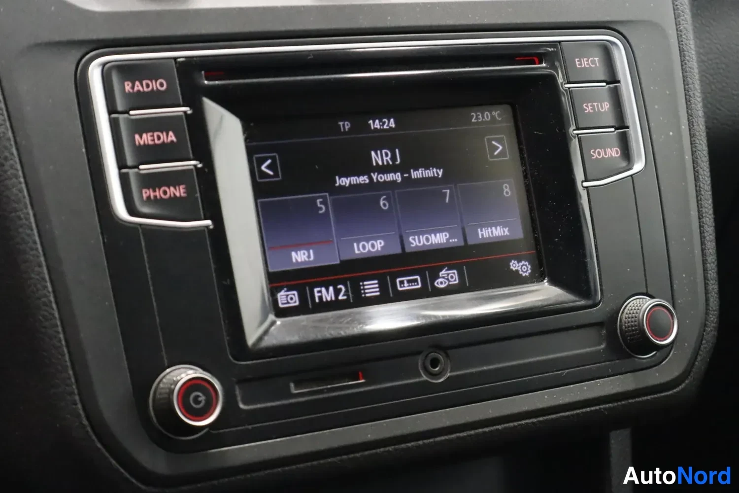 Yksityiskohta: Volkswagenin radiopaneeli näytöllä radioasema NRJ kappaleella 'Joymes Young - Infinity', FM 2 -vyöhyke, lämpötila 23,0 °C.
