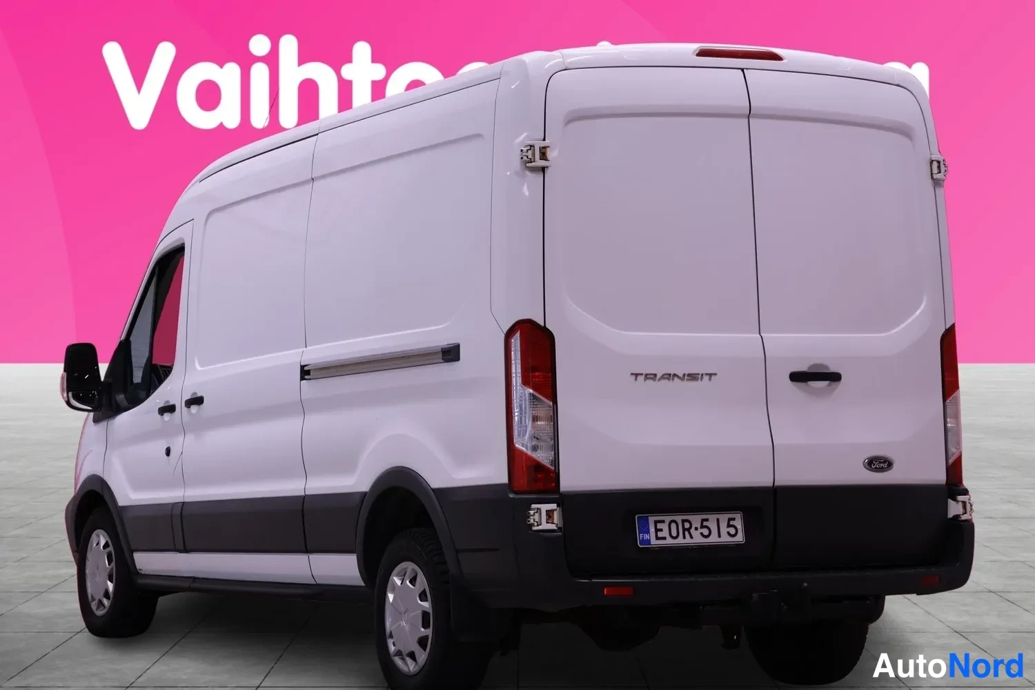 Takaviisto: Pakettiauton takanurkkaus kolmannelta neljännekseltä valkoinen Ford Transit, rekisterikilpi, takavalot ja Transit-merkintä näkyvissä.