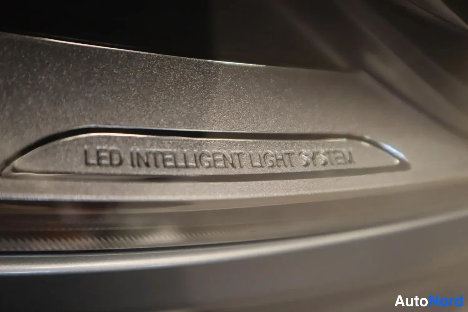 Muu: Lähikuva kirkasmetallisesta valolistasta, johon on kaiverrettu teksti 'LED INTELLIGENT LIGHT SYSTEM'.