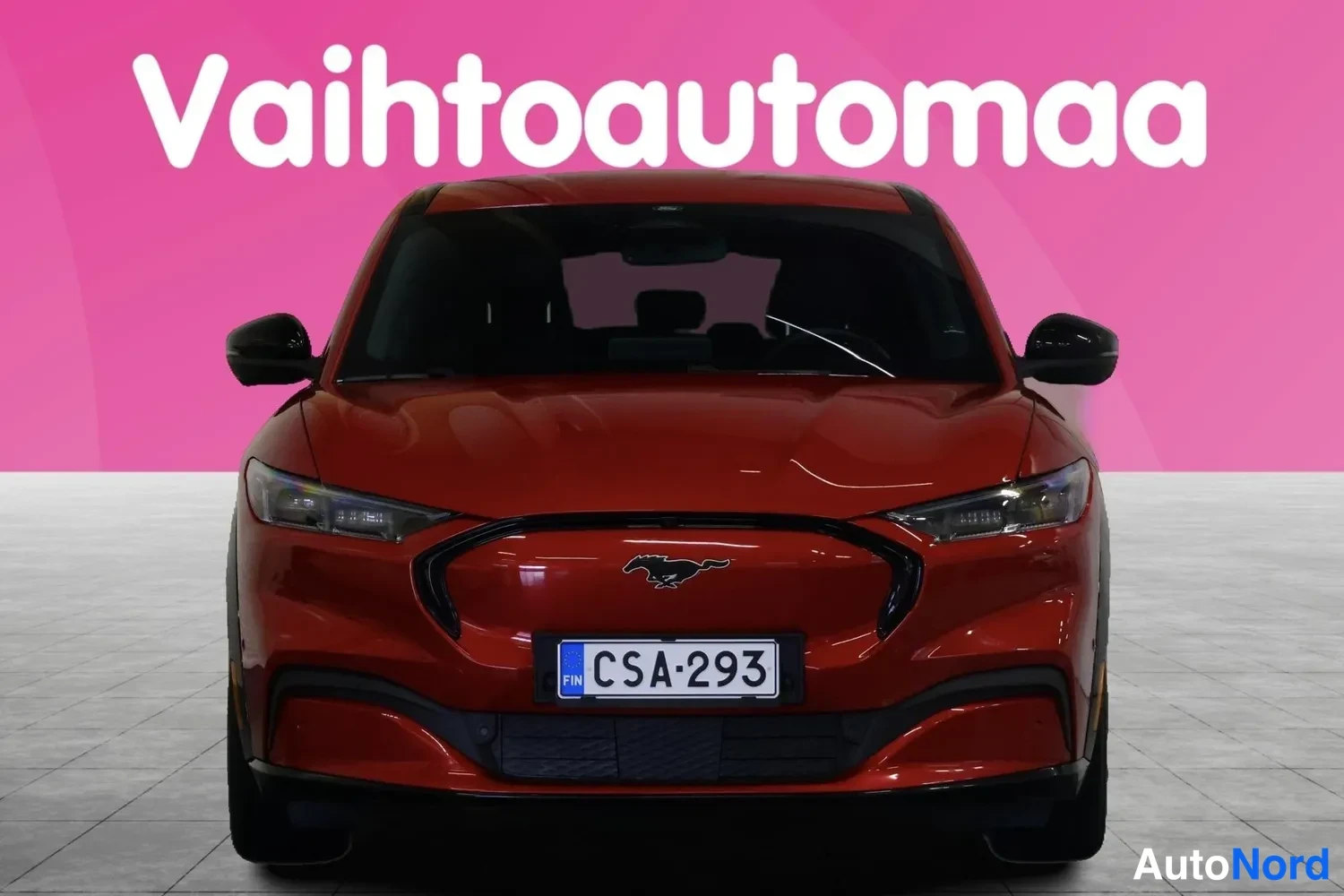Edestä: Punainen Ford Mustang Mach-E suoraan edestä valokuvattu, rekisterissä.