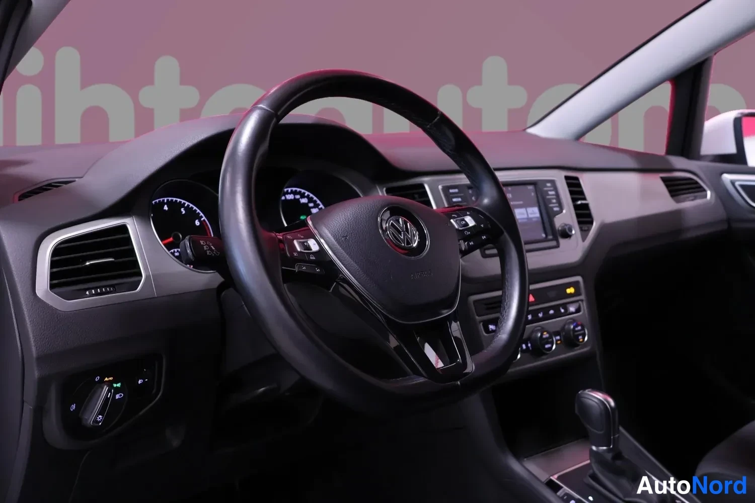 Muu: Ohjaamo Volkswagenissa: ratissa VOLK-logo, mittaristo ja kosketusnäyttö, automaattivaihteen valitsin keskikonsolissa.