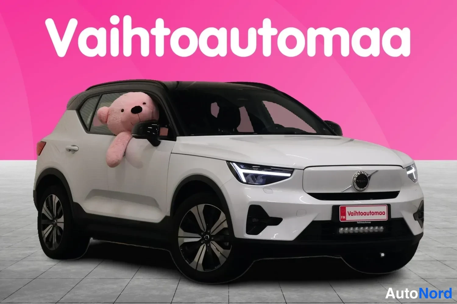Etuviisto, nokka oikealle: Valkoinen Volvo XC40 kulmasta edestä oikealta, valot päällä.