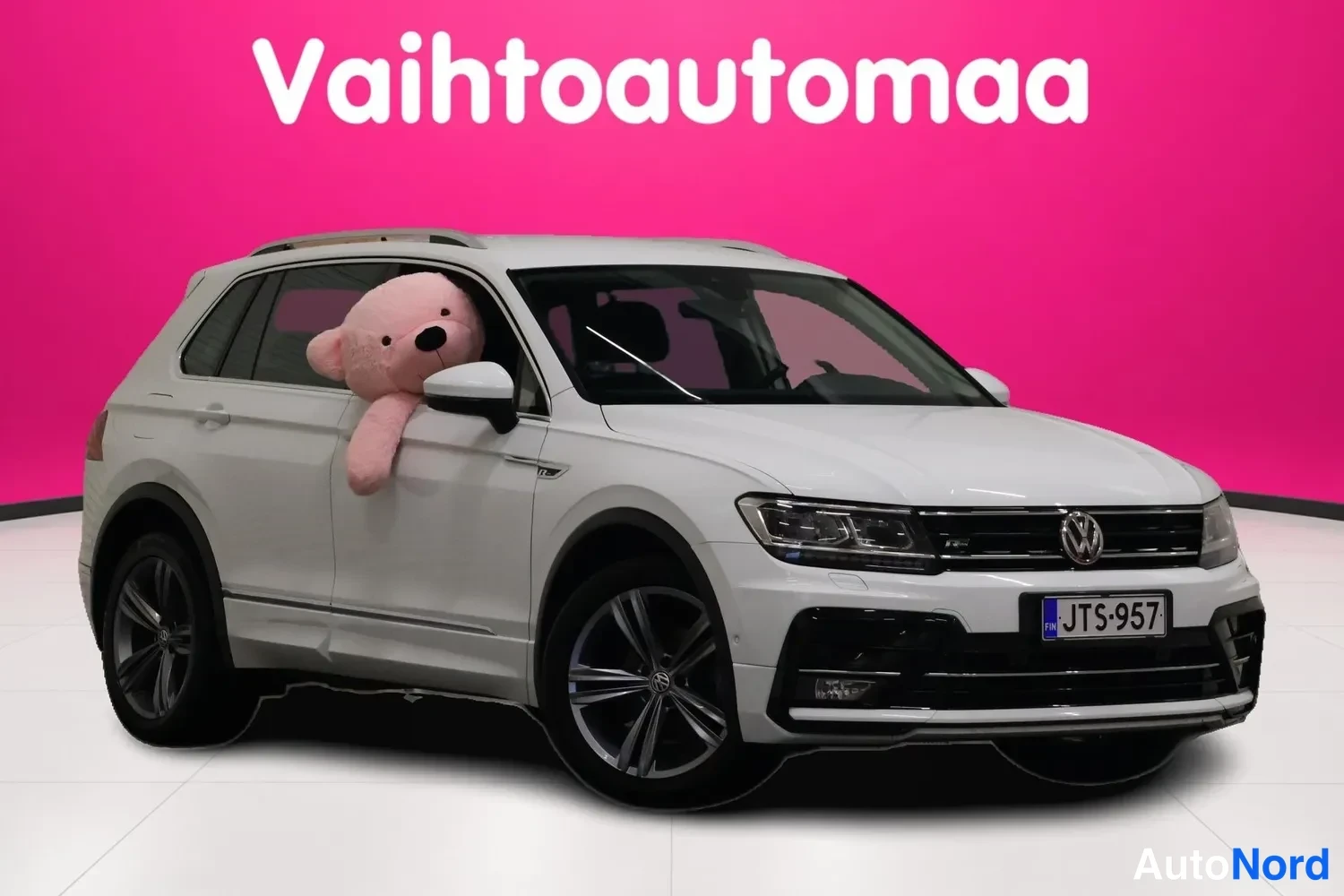 Etuviisto, nokka oikealle: Valkoinen Volkswagen Tiguan kulmatelineessä, keula oikealla, rekisteritunnus.