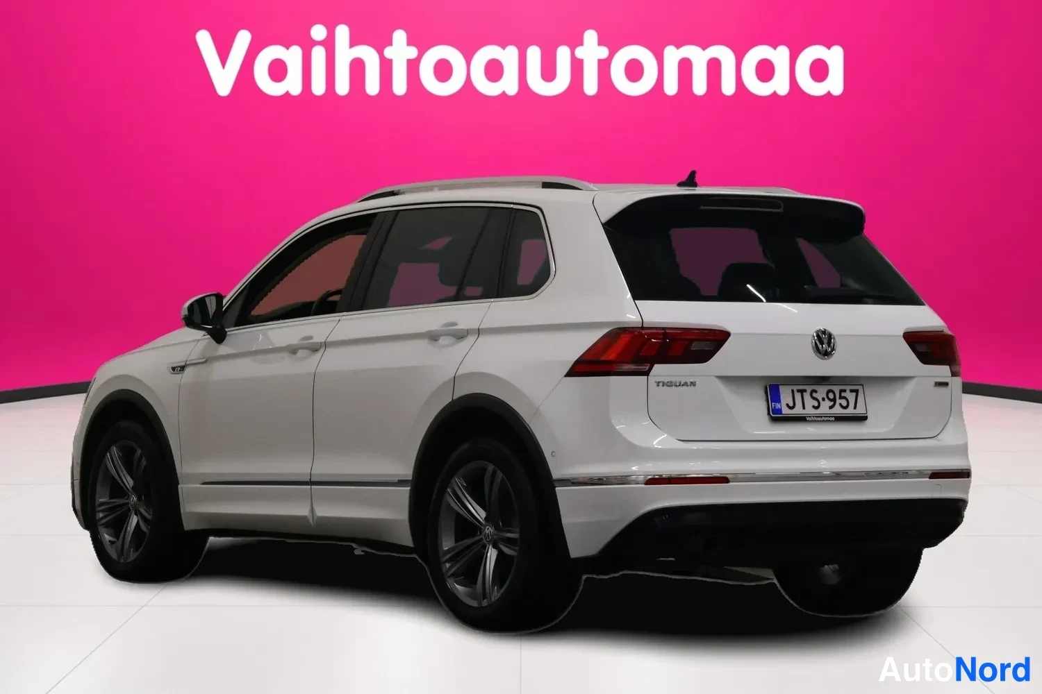 Takaviisto: Auton takakulmanäkyvyys: valkoinen Volkswagen Tiguan -farmerimaasturi, takavalot, rekisterikilpi, kattokaiteet ja tummat vanteet.