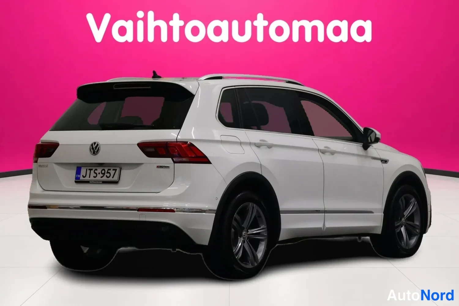 Takaviisto: Auton takakulmanäkyvyys toisesta suunnasta: valkoinen Volkswagen Tiguan -maasturi, rekisterikilpi, kattokaiteet ja alumiinivanteet.