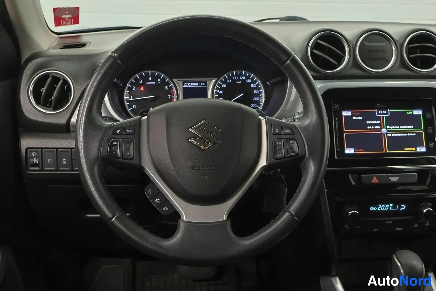 Muu: Ohjauspyörän tarkempi kuva: Suzuki-logo, mittaristo ja kosketusnäytön bluetooth-valikko.