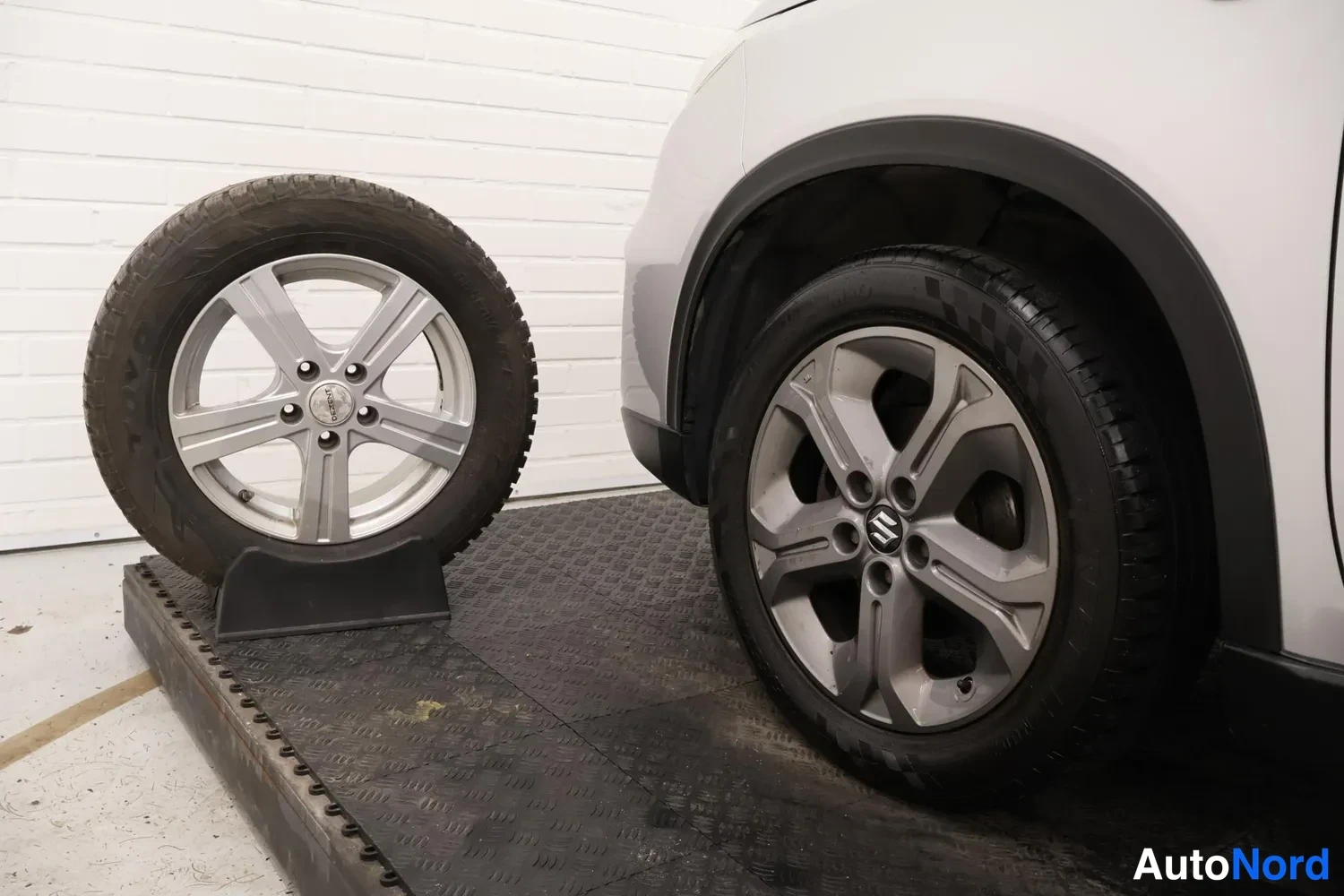 Muu: Suzuki-merkitty kevytmetallivanne auton pyörässä ja varapyörä telineessä vierellä.