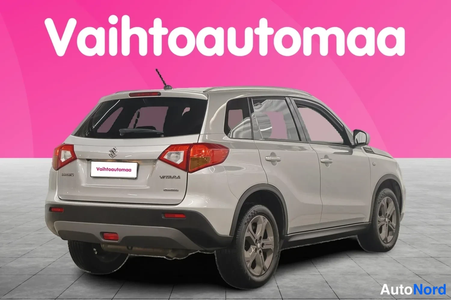Takaviisto: Auton takapää ja oikea sivu kolmannesvinkkelissä: hopeanharmaa crossover, jonka takavalojen väliin on asetettu Vaihtoautomaakyltti; korin pinnat ja takapyörät n