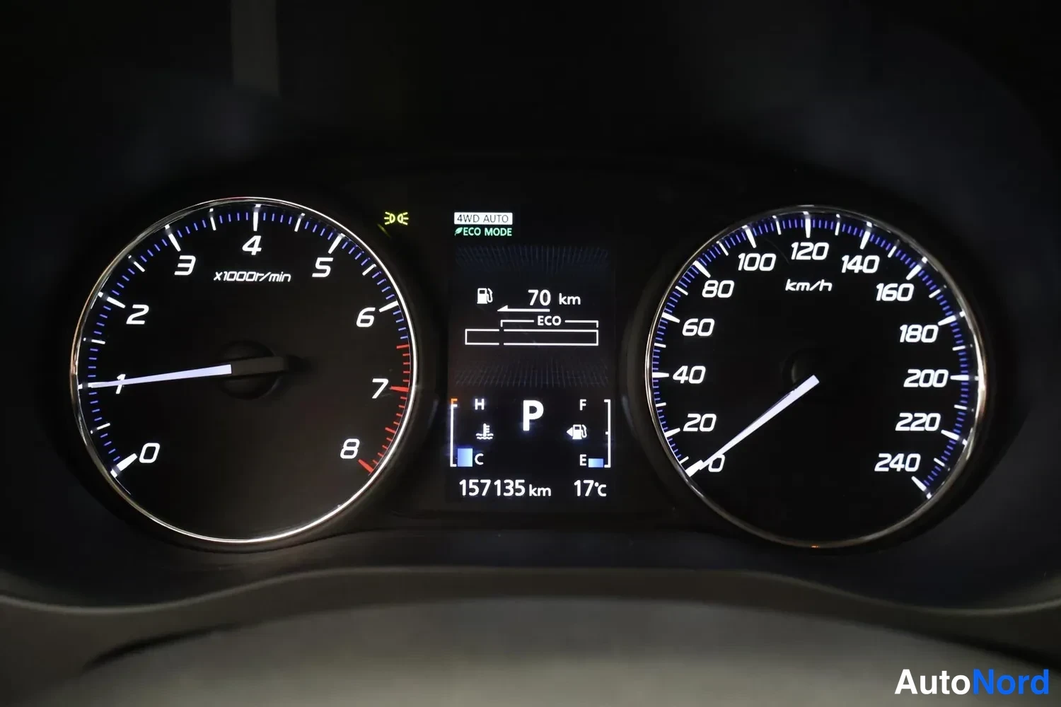 Yksityiskohta: Sisätilakuva: kojelaudan mittaristo, jossa lukema 157135 km, ajotietokoneen ilmoittama 70 km jäljellä ja 4WD AUTO sekä ECO MODE -valinnat, vaihteiston P-tila.