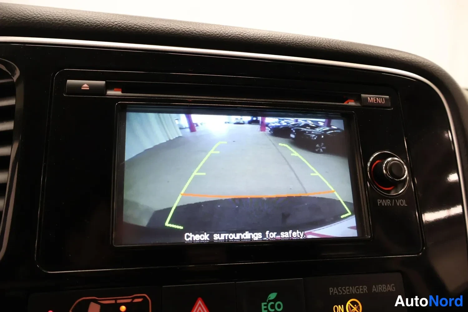 Muu: Autoinfo näyttää peruutuskameran kuvaa ohjausviivoineen ja tekstin Check surroundings for safety.
