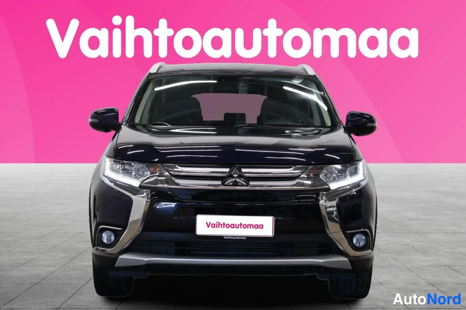 Edestä: Tummansininen farmariauto suoraan edestä kuvattuna, etusäleikkö ja ajovalot näkyvissä.