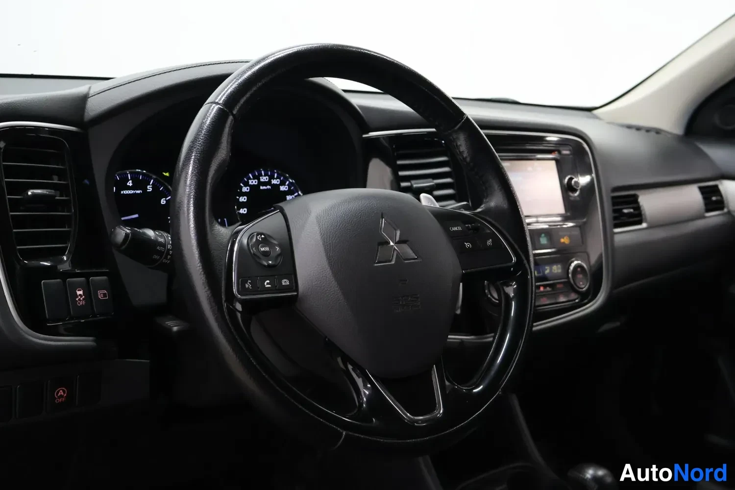Muu: Ohjaamossa näkyy Mitsubishi-merkitty ohjauspyörä, mittarit ja keskikonsoli, kuva sisätiloista.