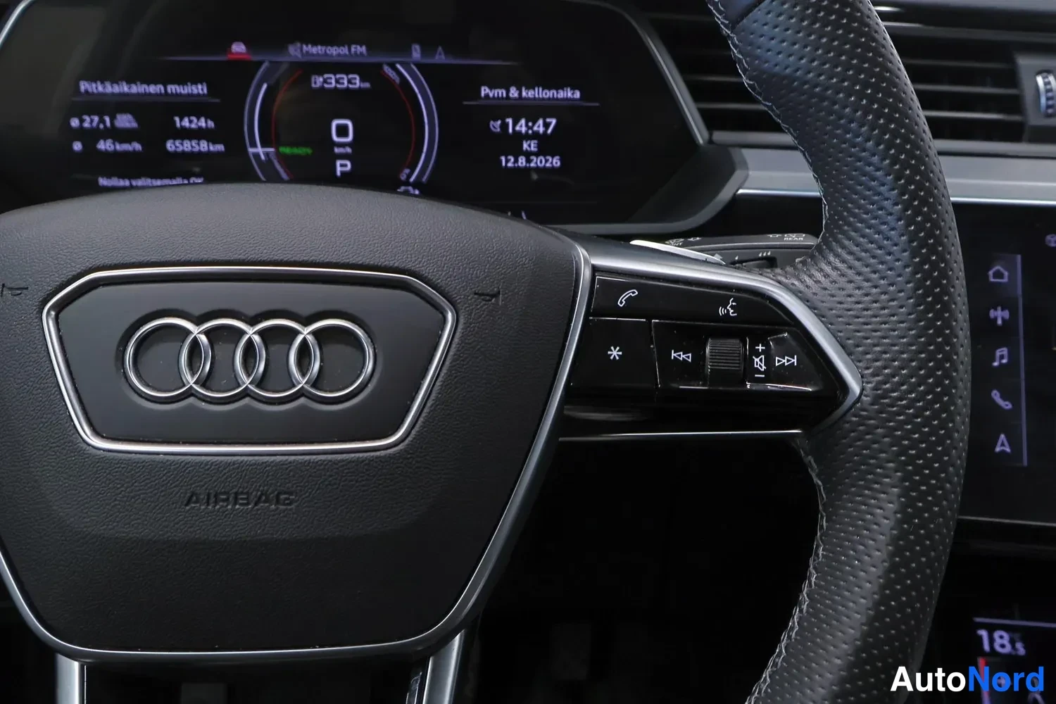 Muu: Audi-ohjauspyörän AIRBAG-merkintä ja merkkipainikkeet, taustalla digitaalinen mittaristo, jossa näkyy kokonaismatka 65858 km, vaihde P ja kellonaika 14:47.