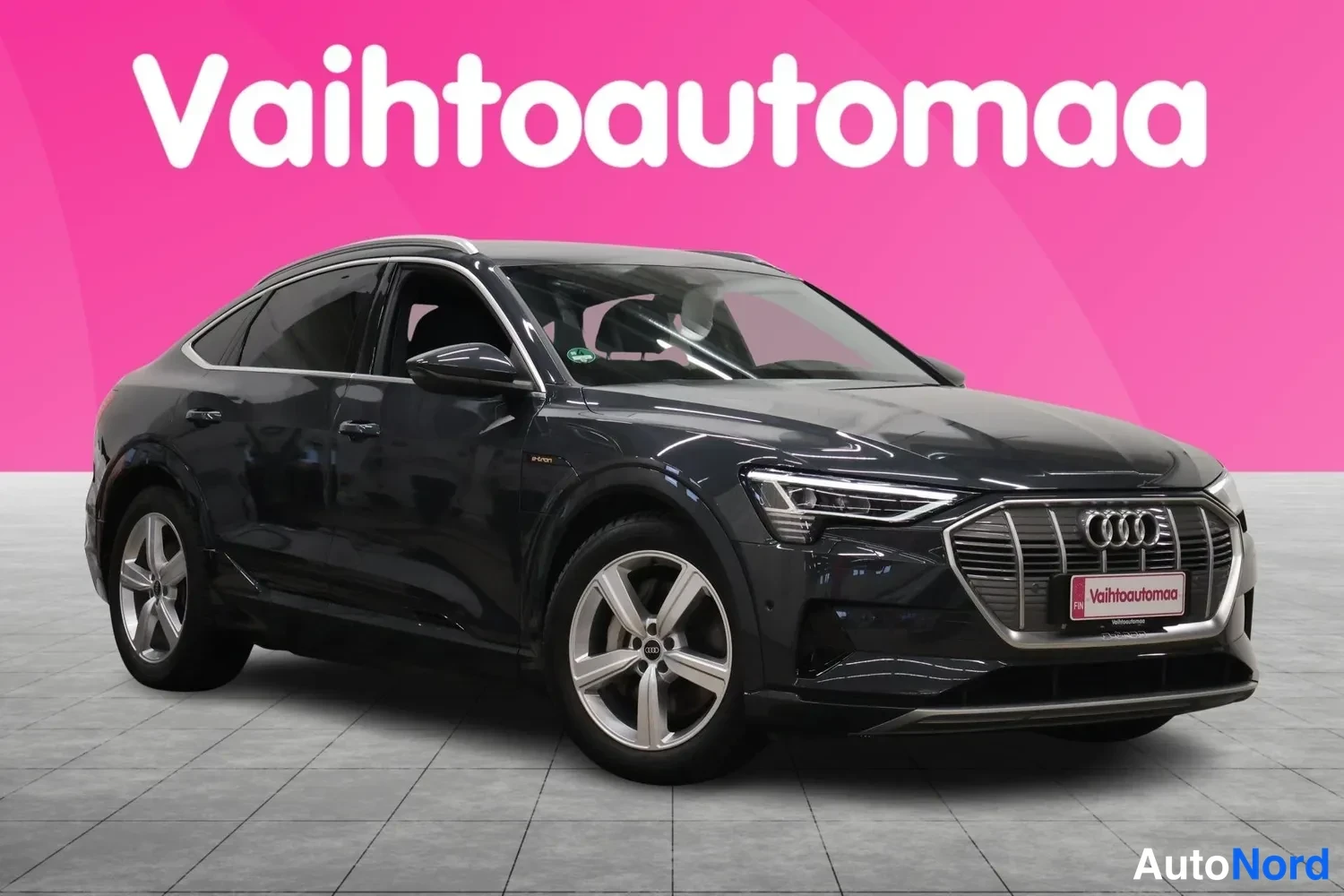 Etuviisto, nokka oikealle: Audi e-tron Sportback, tummanharmaa, etukulmasta oikealta, musiikkinaula taustalla