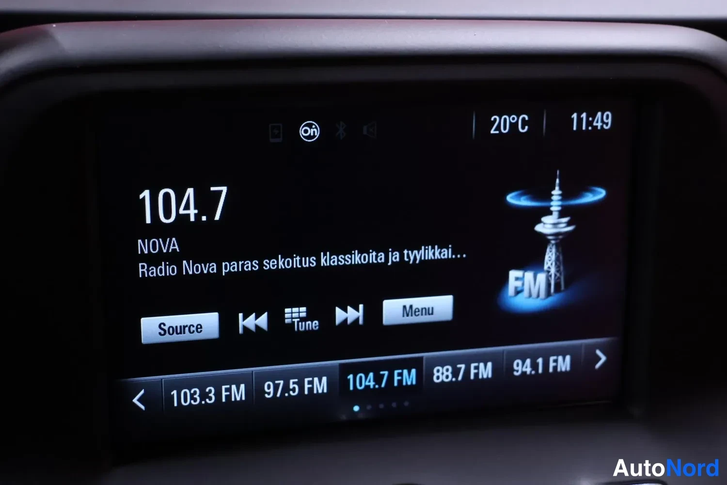 Yksityiskohta: Viritin, jossa teksti 104.7, NOVA, Radio Nova paras sekoitus klassikoita ja tyylikkai…, 20°C, 11:49, Source, Tune, Menu ja FM-asemalistaus.