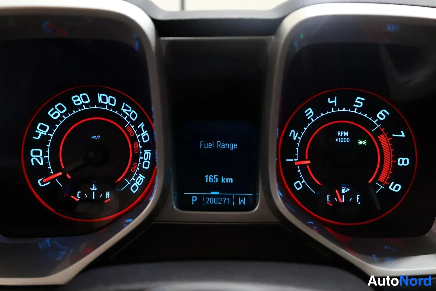 Yksityiskohta: Mittaristön tarkempi kuva: nopeusmittari, kierroslukumittari ja keskinäyttö, jossa lukee Fuel Range 165 km ja kilometrilukema 200271.