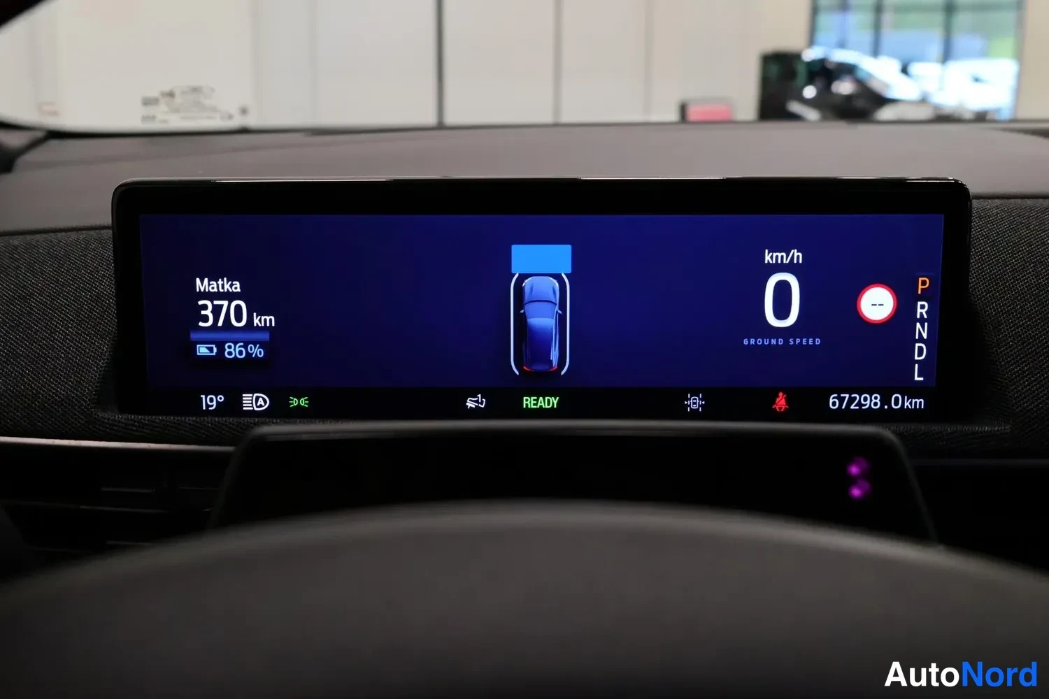 Takaa: Kojelaudan digitaalinen mittaristo näyttää matkaa 370 km, akun varautumista 86 %, nopeutta 0 km/h,:a vaihdelaatikon asentoa P ja kokonaismäärää 67298,0 km.