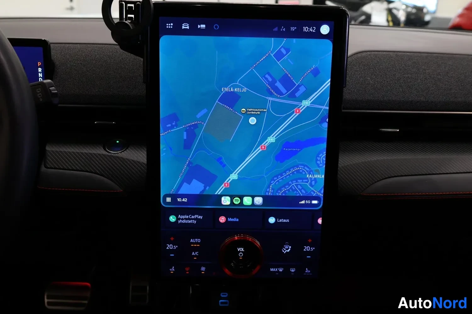 Muu: Pystysuora infotainment-näyttö autossa näyttää navigointikarttaa; alareunassa Apple CarPlay, Media ja Lataus sekä lämpötila-asetukset 20,5 asti.